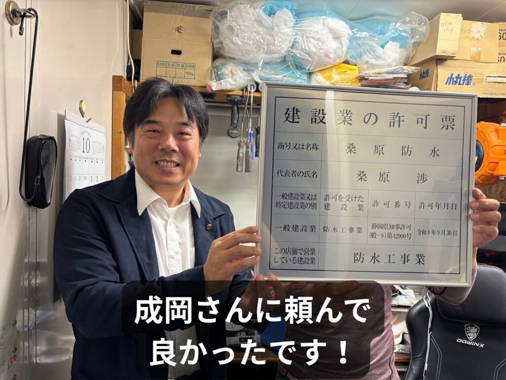 桑原防水様の建設業許可票を持つ桑原様と行政書士の成岡。「成岡さんに頼んで良かったです!」とのご感想。